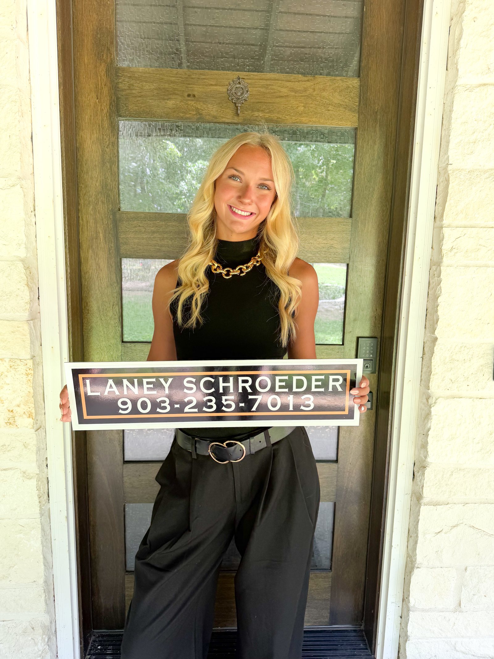 Laney Schroeder holding her real estate sign outside a home